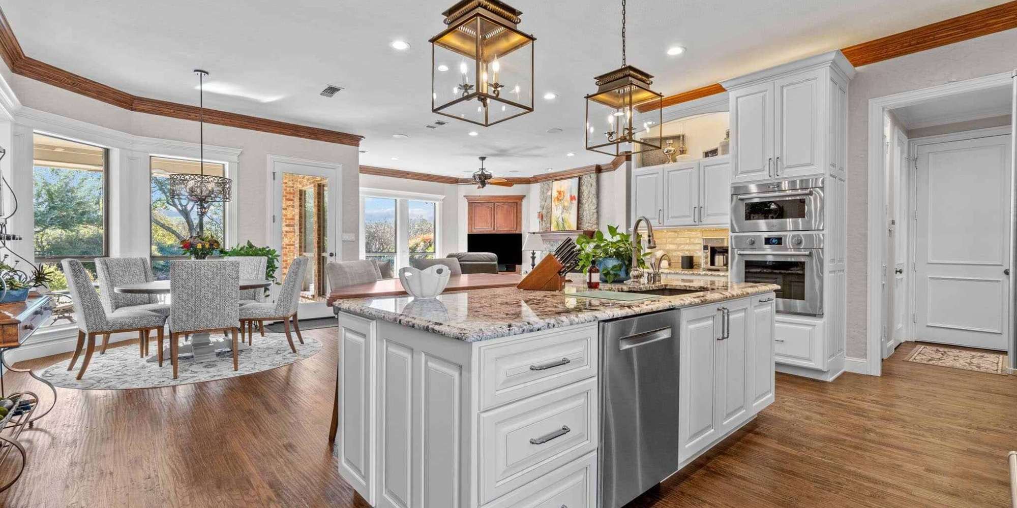 Image of kitchen remodel with large island, white cabinetry, and pendant lighting in Collin County by Elite Remodeling
