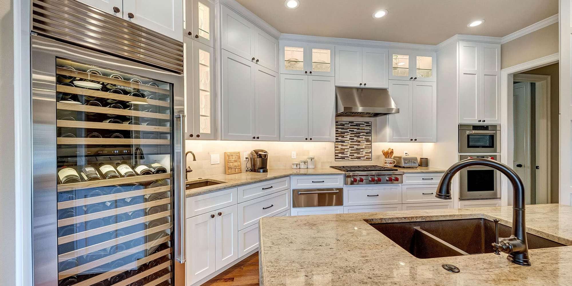 Image of upscale kitchen with wine fridge, white cabinets, and granite countertops in Collin County by Elite Remodeling