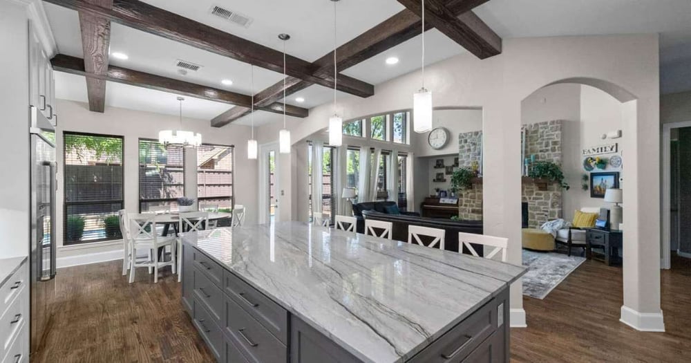 Image of open kitchen remodel with large island, wood beams, and modern lighting in Collin County by Elite Remodeling
