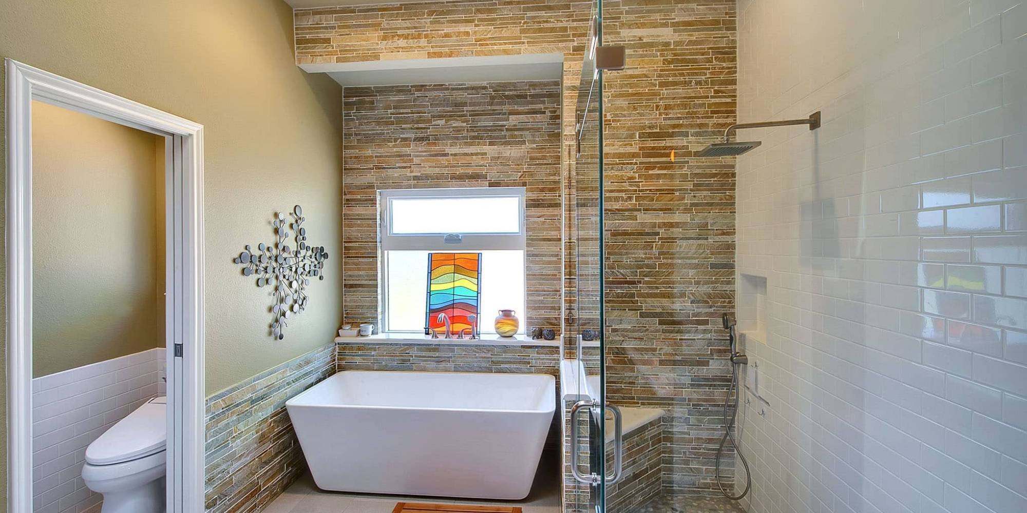 Luxurious bathroom remodel in Frisco, TX with vibrant stained-glass decor and sleek glass shower enclosure by Elite Remodeling