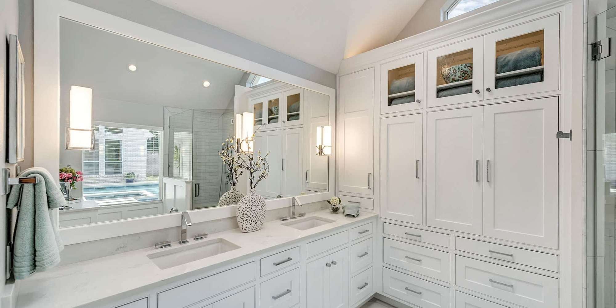Bathroom remodel with dual sink vanity and cabinet storage by Elite Remodeling