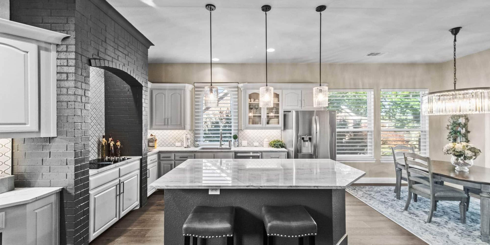 Gray shaker kitchen cabinets with marble island and black brick accent wall by Elite Remodeling