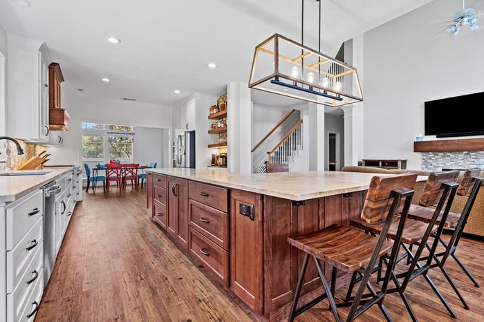 Custom home remodel in Frisco, TX with dark wood cabinetry and flooring with view of living room from open floor kitchen and dining area