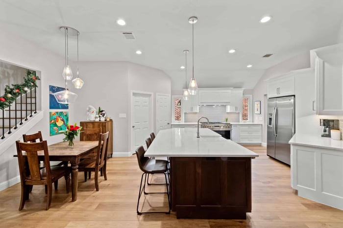 Remodeled kitchen in Frisco, TX with a large granite island and white cabinetry