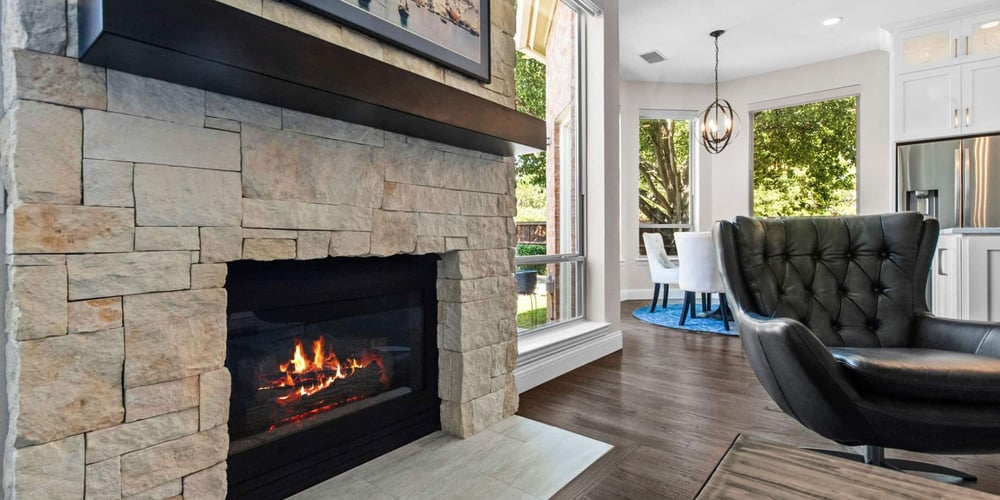 Image of a remodeled living room with wood flooring and a stone feature fireplace in Frisco, TX